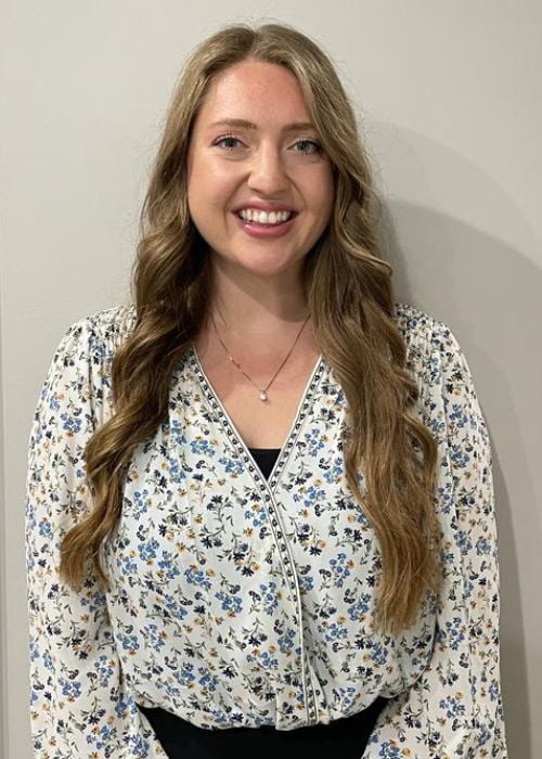 Photo of blonde haired woman, looking at the camera, smiling.