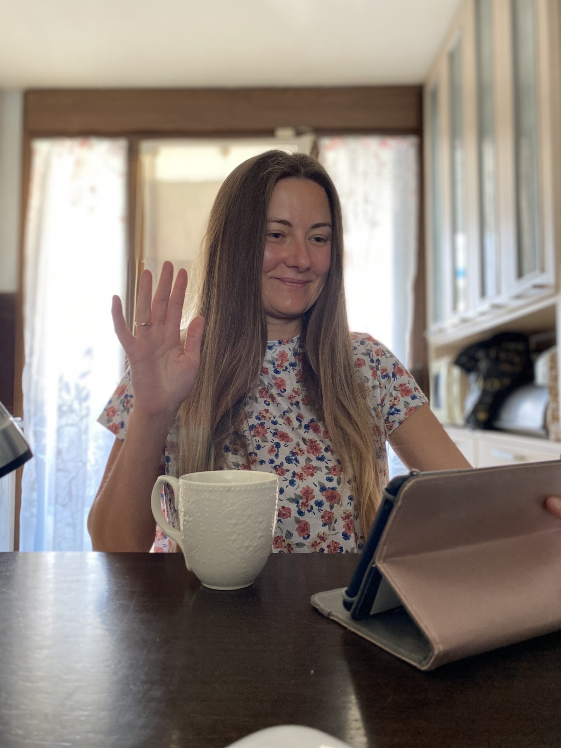 Woman working from home on tablet with a cup of coffee