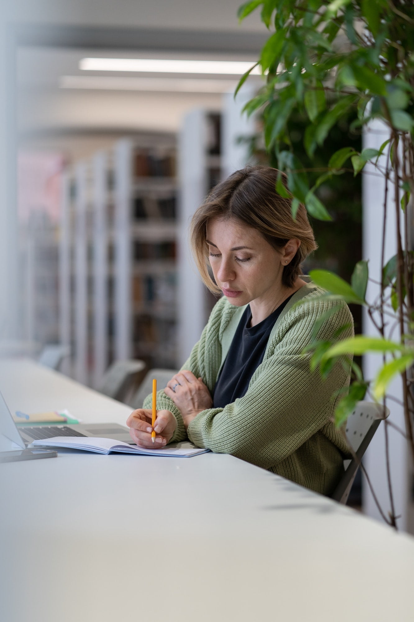 Female taking notes in day planner while sitting in library