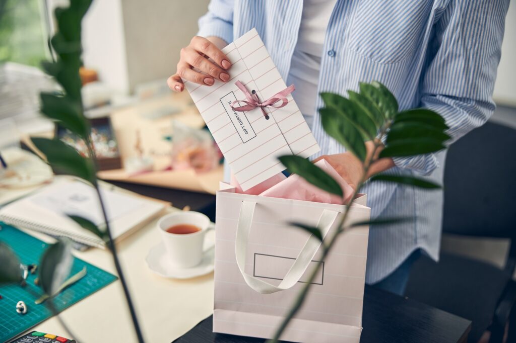 Female out of focus adding branded cards to client gifts