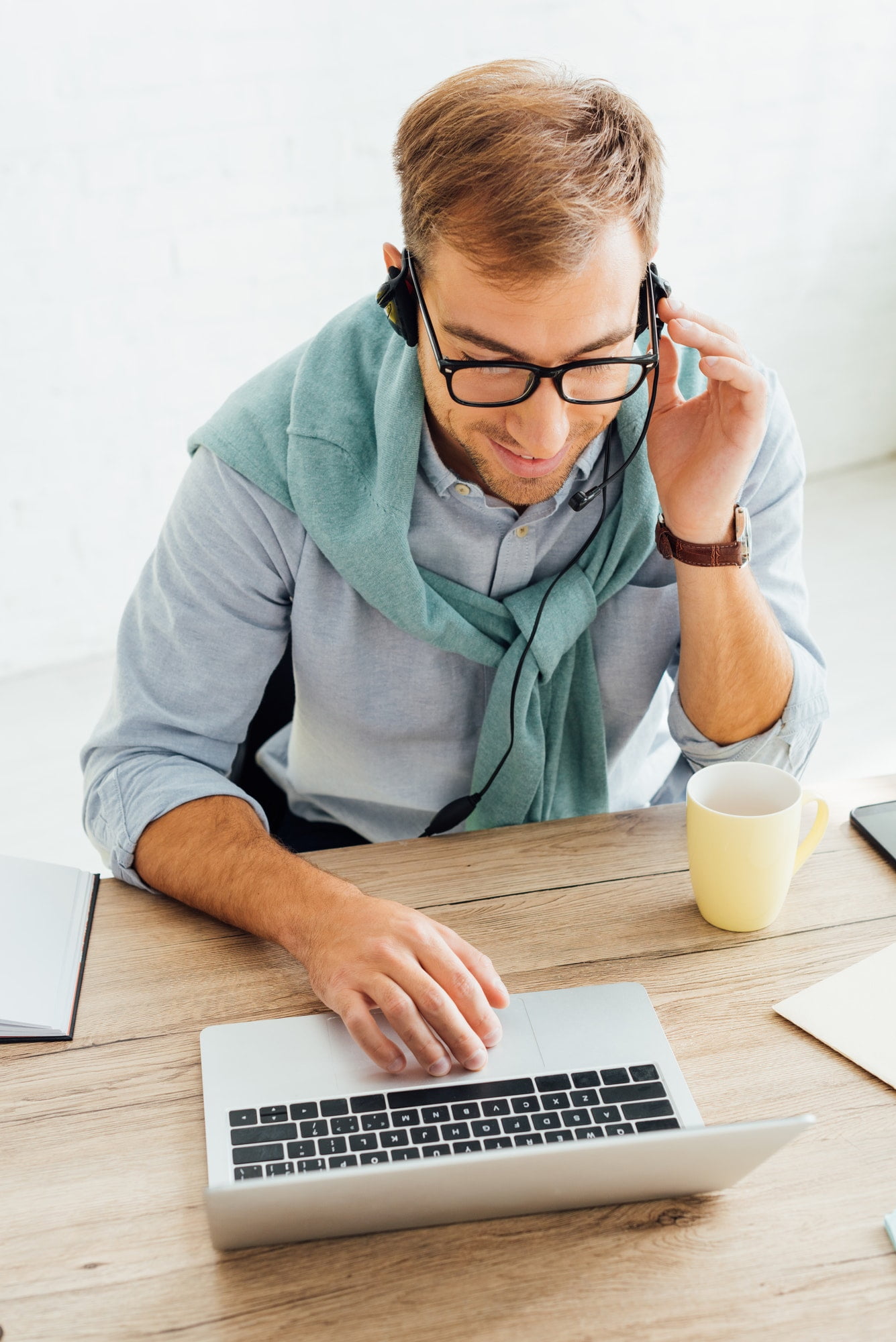 Male wearing headset working on laptop and talking on the phone