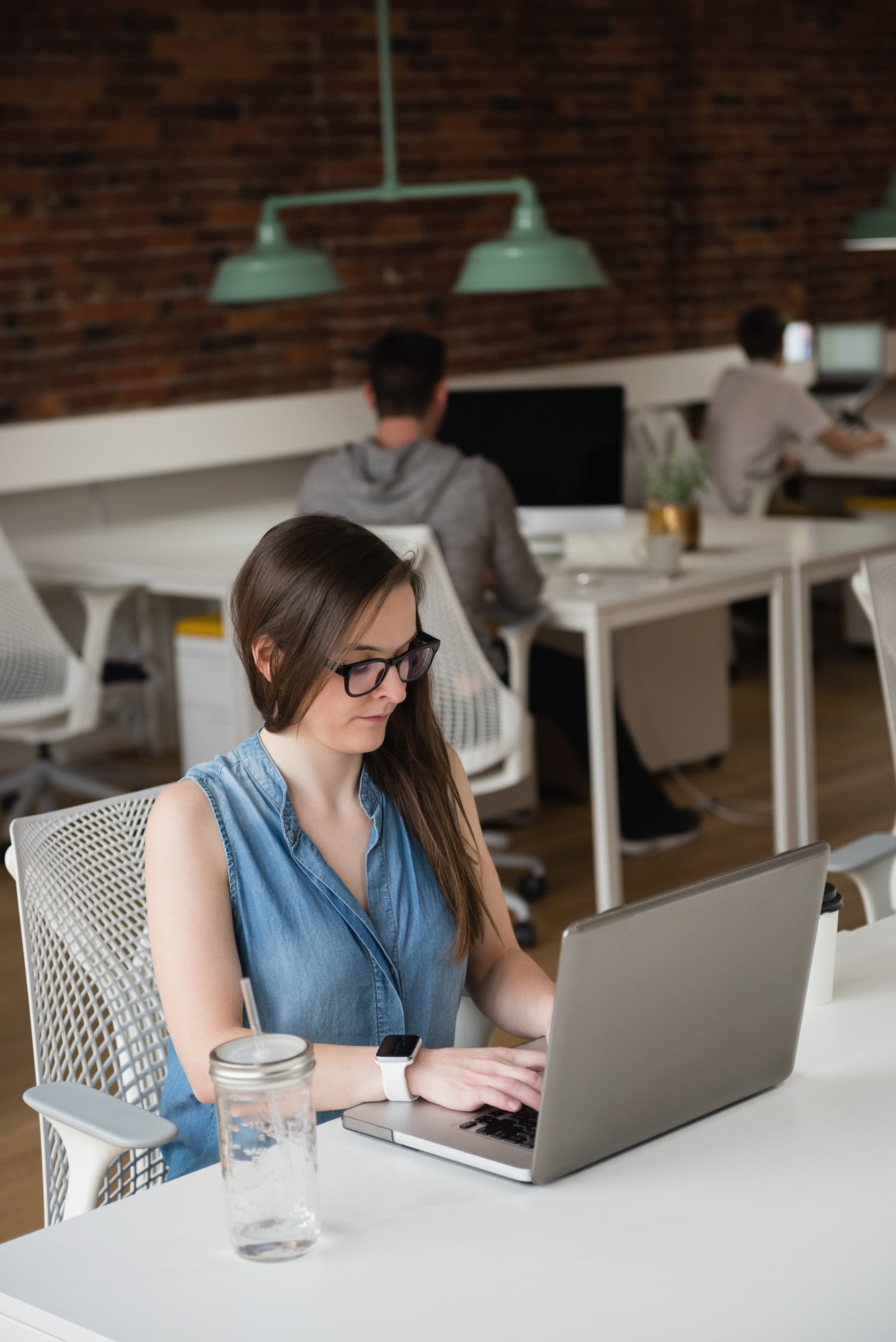 Female working on laptop with office in the background