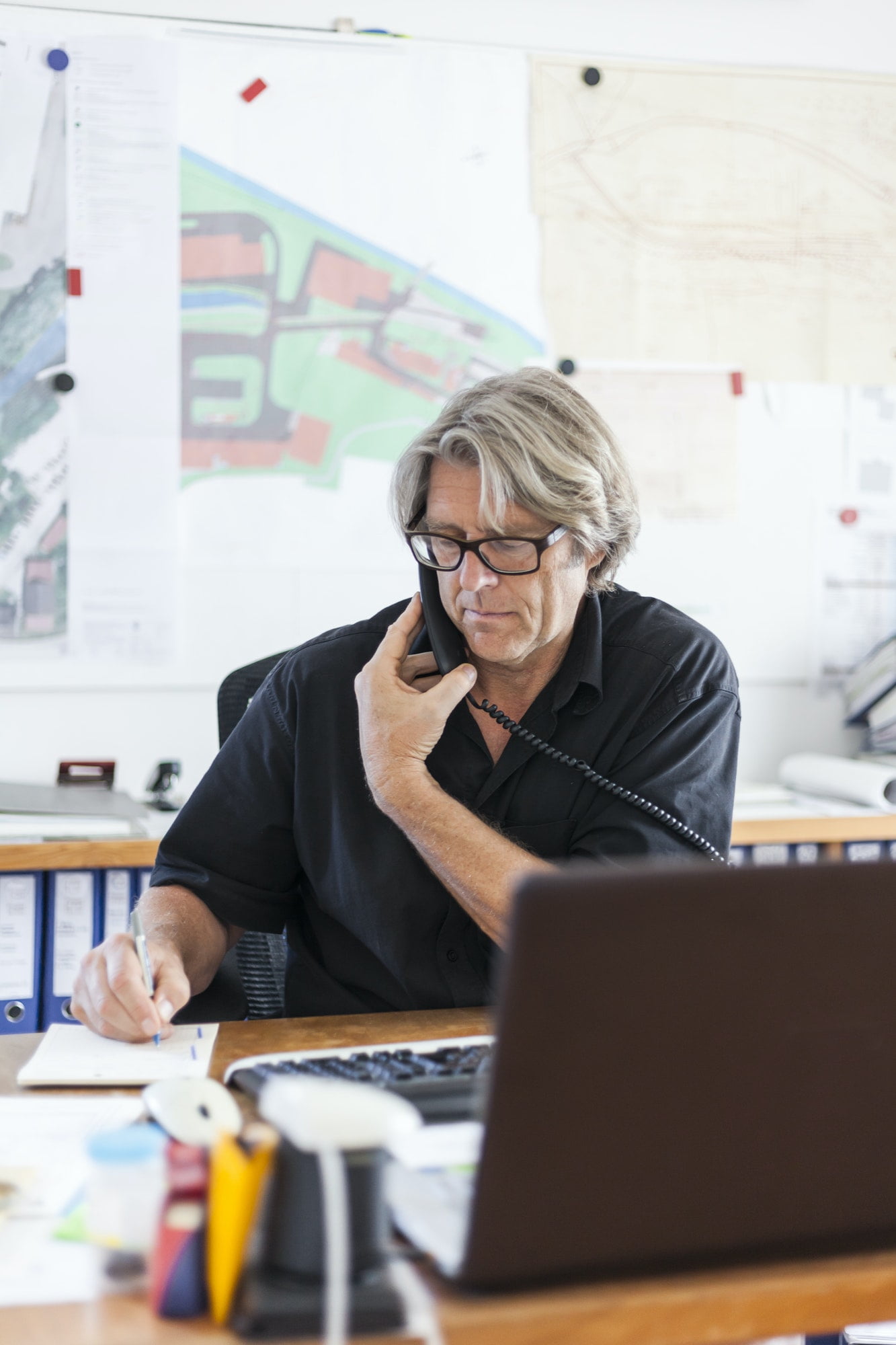 Mature man telephoning at desk in his office