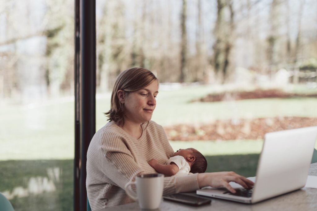 New Mum working on laptop while holding baby