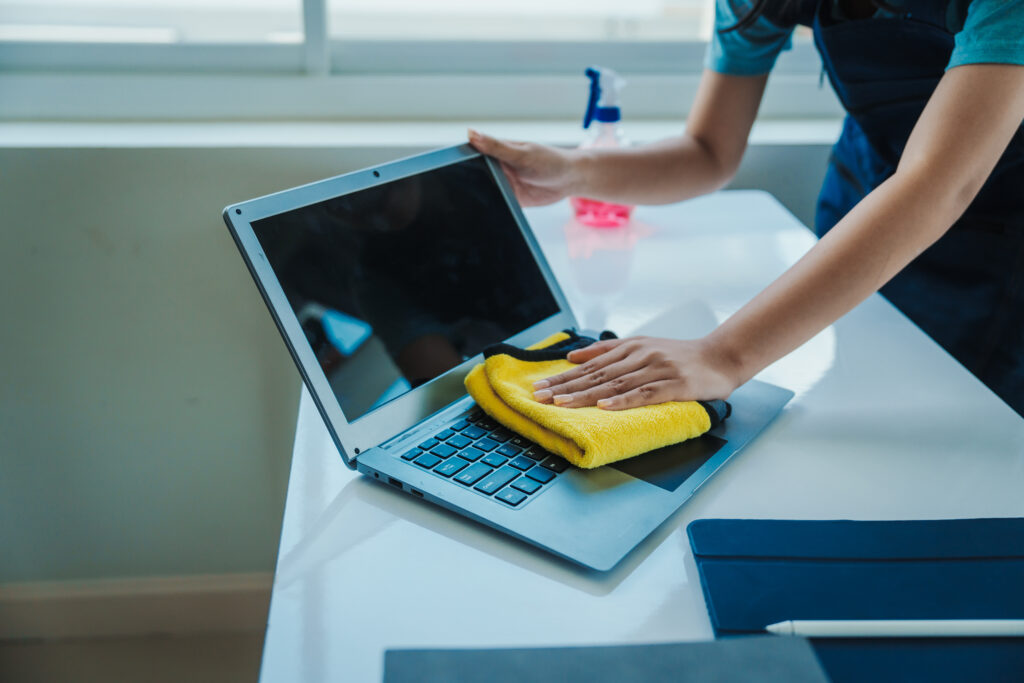 Woman cleaning her laptop with a dry cloth, showing you how to look after your computer.